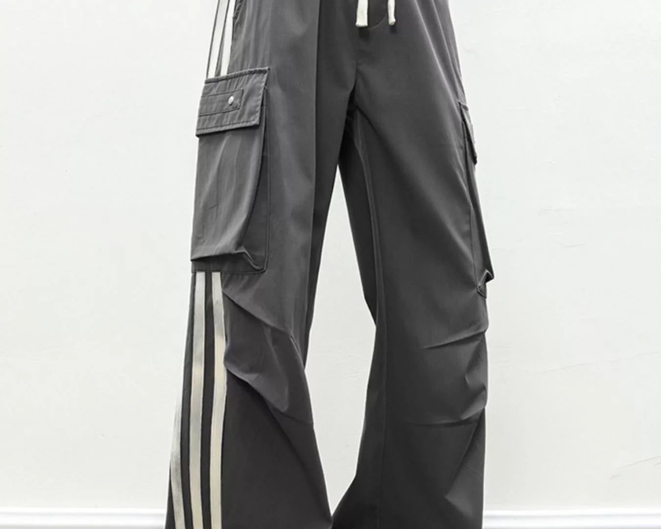 NEWYORKLISTED ATLAS MEN's COLLECTION: Person wearing gray cargo pants with white stripes and white sneakers on a plain background