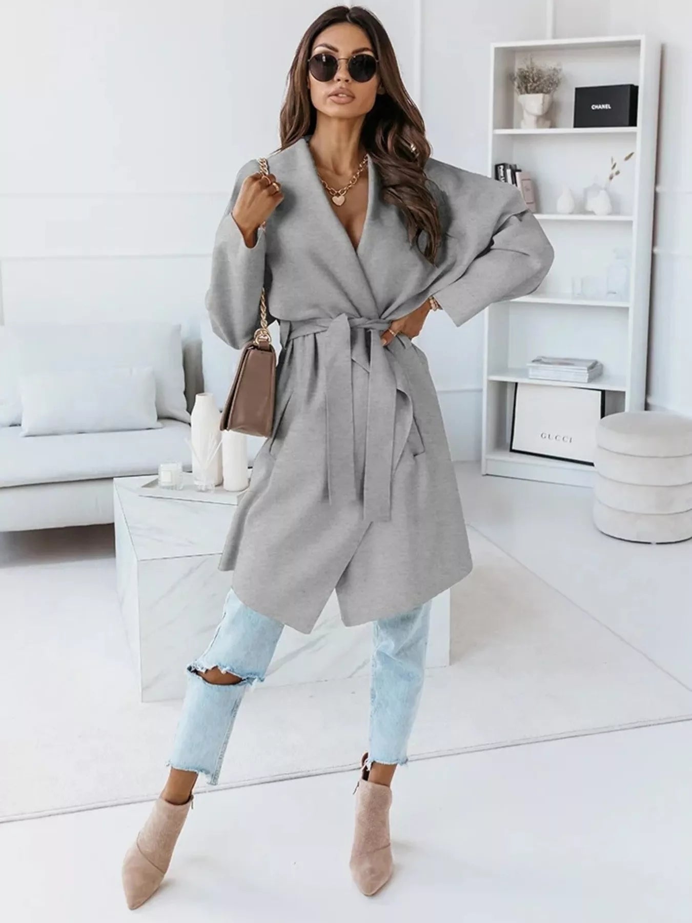 NEWYORKLISTED STYLE COLLECTION: Woman wearing a gray coat in a modern living room