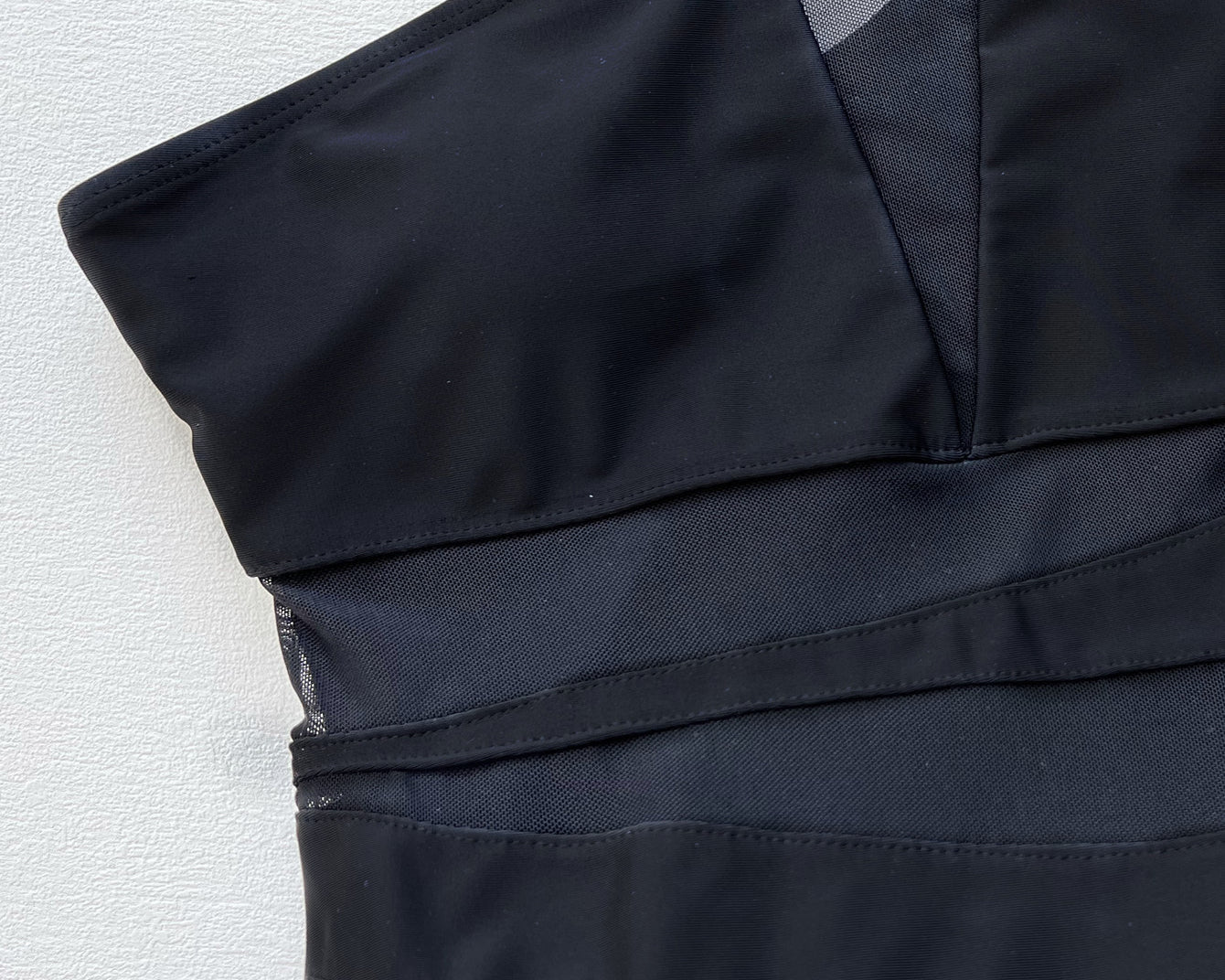 NEWYORKLISTED Eden Collection: One-Shoulder Sleeveless One-Piece Swimsuit Black strapless dress on a textured white background