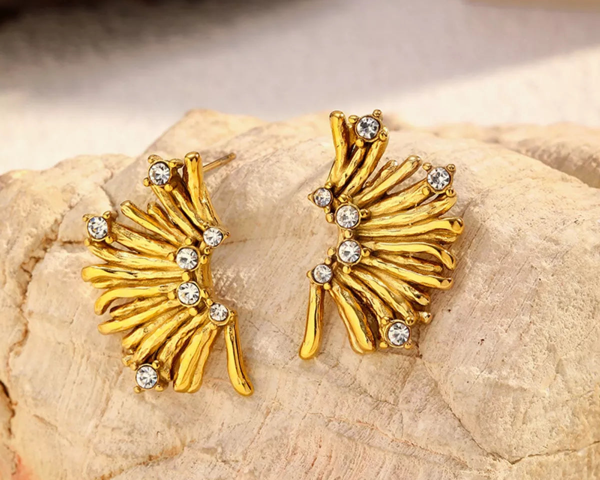 NYLD Glamour Collection by NEWYORKLISTED: Gold earrings with gemstones on a stone surface