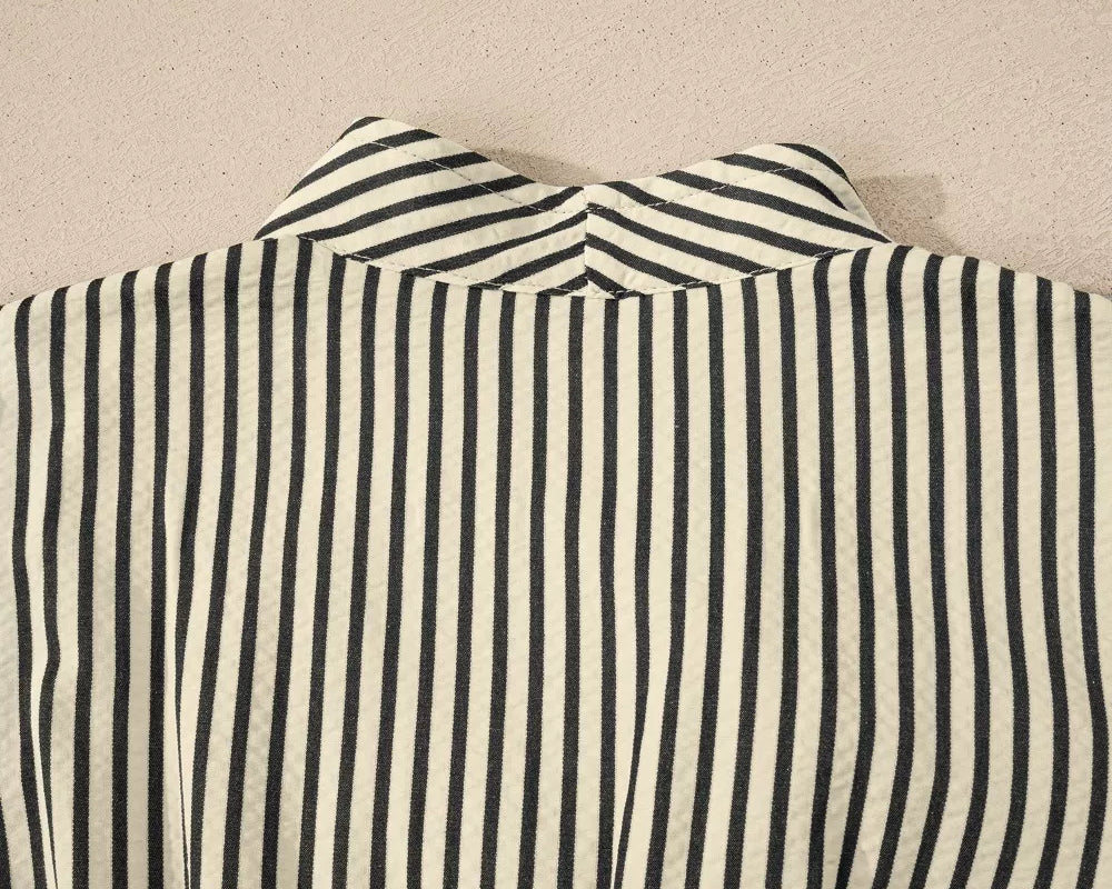 NEWYORKLISTED STYLE COLLECTION: Close-up of a black and white striped shirt collar on a beige background