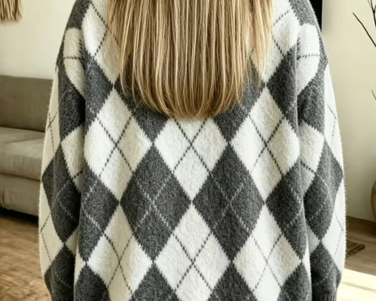 NEWYORKLISTED STYLE COLLECTION: A woman viewed from behind wearing a fuzzy knit sweater with a large gray and off-white argyle pattern, paired with light blue jeans in a home setting.