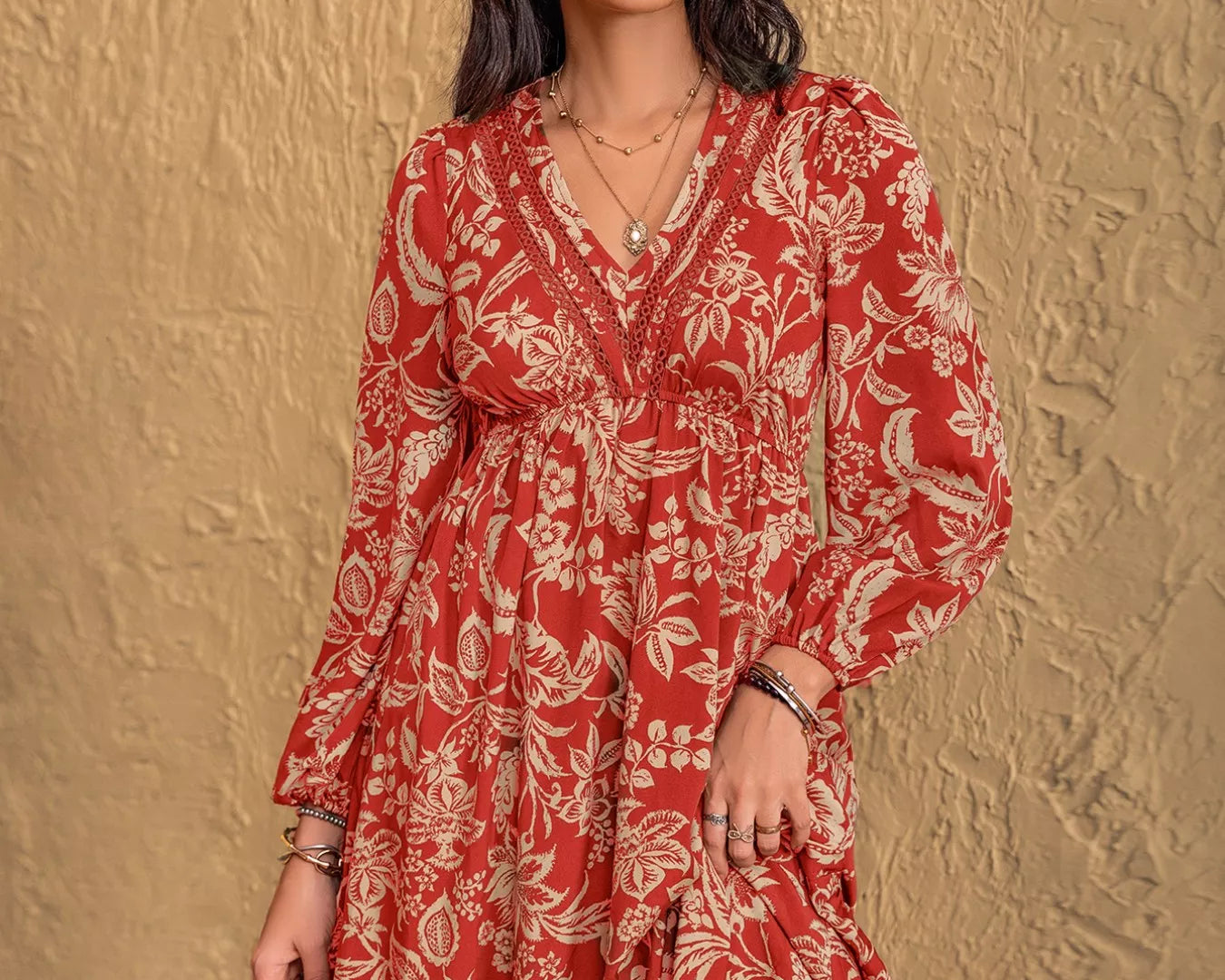 NEWYORKLISTED STYLE COLLECTION: Woman wearing a red floral dress against a textured beige wall