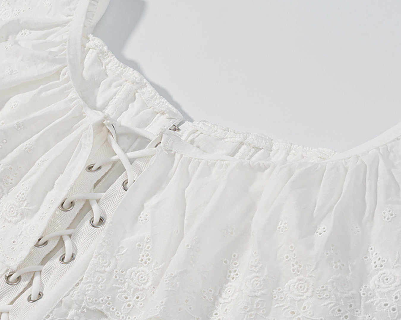 NEWYORKLISTED STYLE COLLECTION: White lace top with intricate detailing on a light gray background
