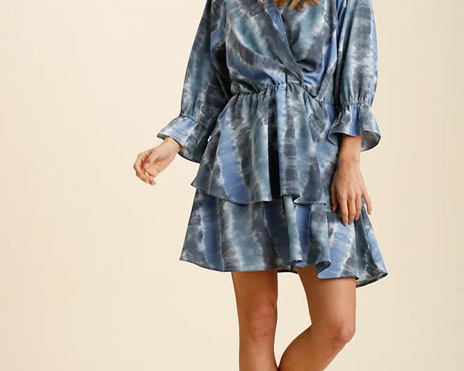 NEWYORKLISTED STYLE COLLECTION: Woman wearing a blue tie-dye dress on a beige background