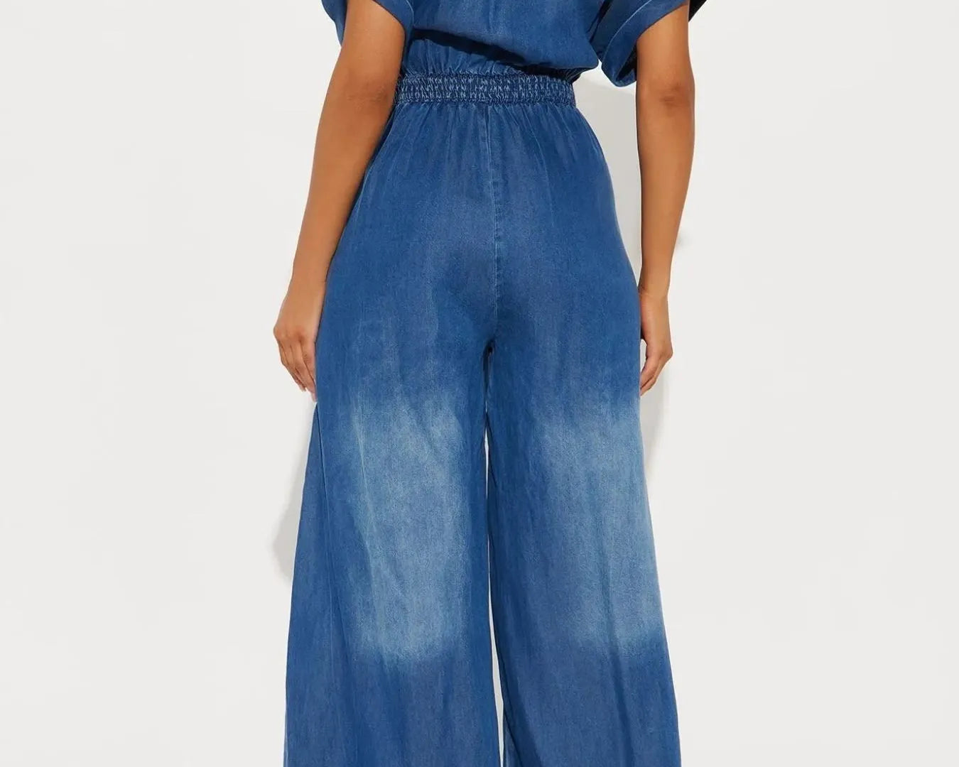 NEWYORKLISTED STYLE COLLECTION: Blue denim jumpsuit worn by a model on a white background