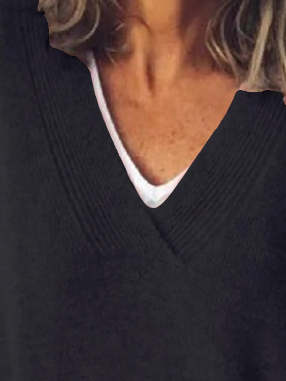 NEWYORKLISTED STYLE COLLECTION: Close-up of a person wearing a dark sweater with a white collar.