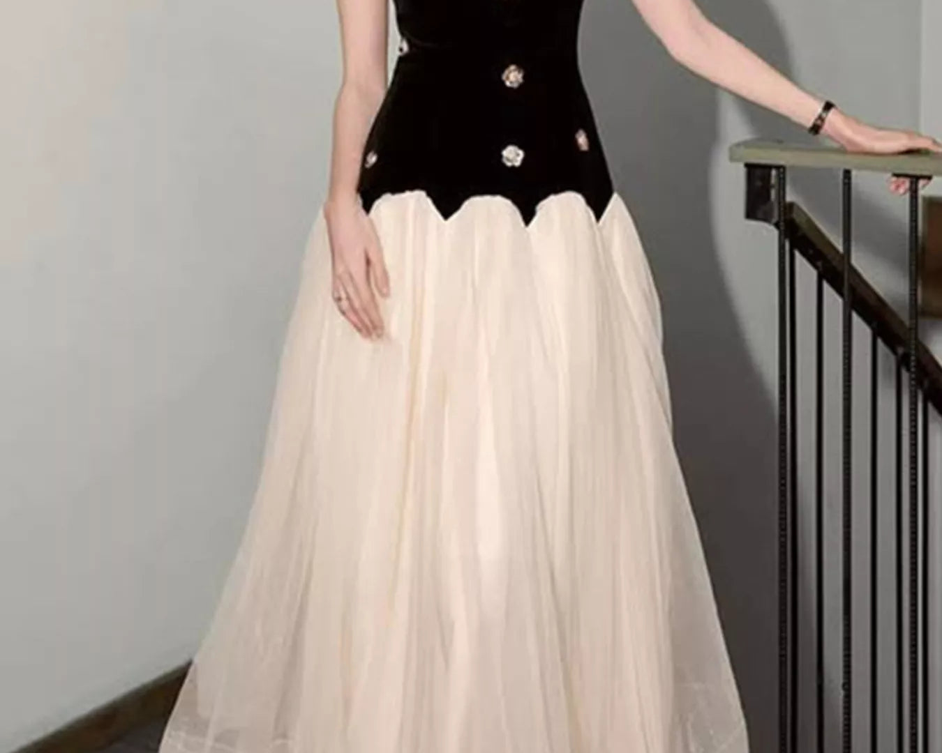 NEWYORKLISTED STYLE COLLECTION: Woman wearing a black top with white embellishments and a beige skirt.