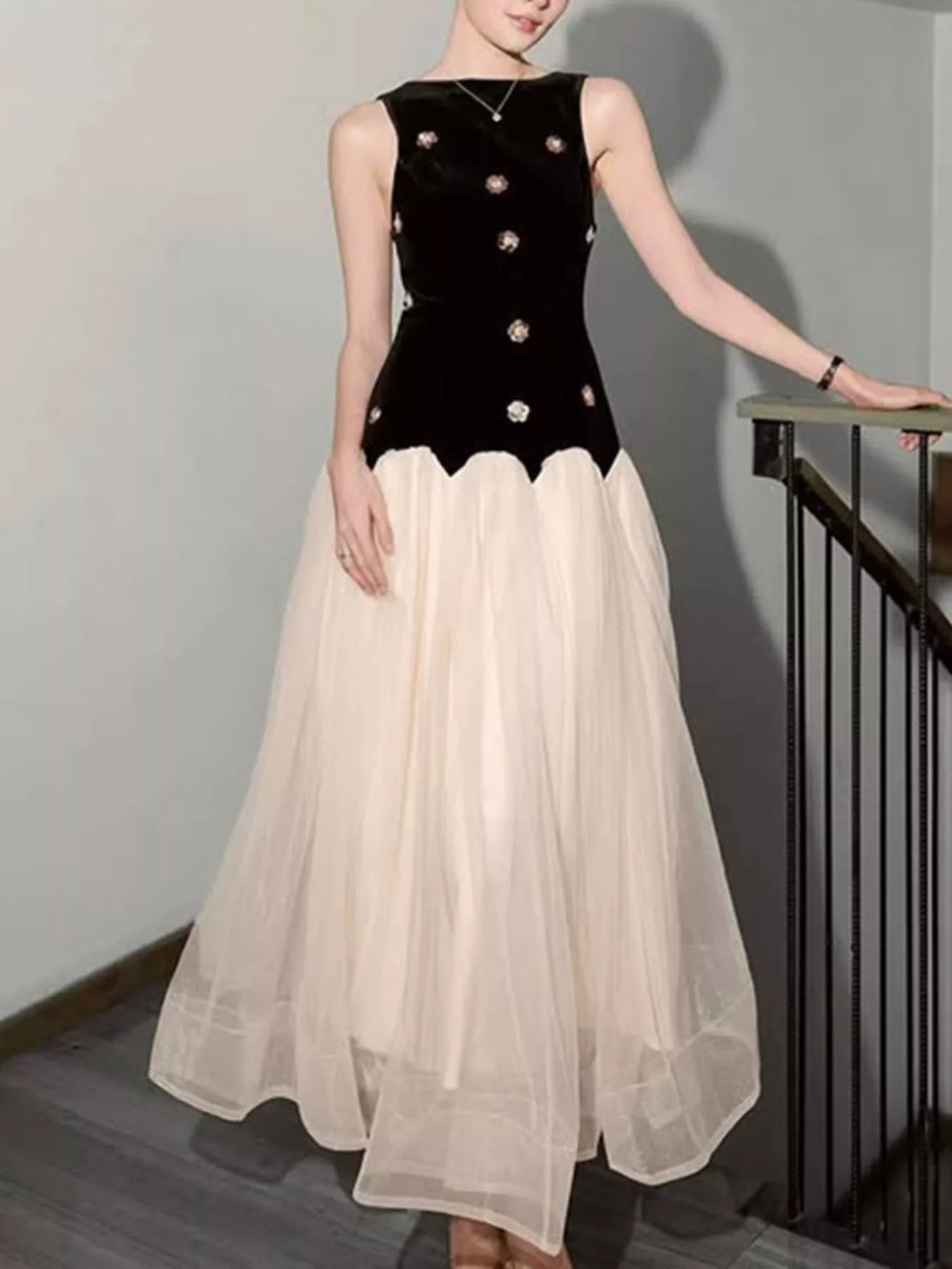NEWYORKLISTED STYLE COLLECTION: Woman wearing a black top with white embellishments and a beige skirt.