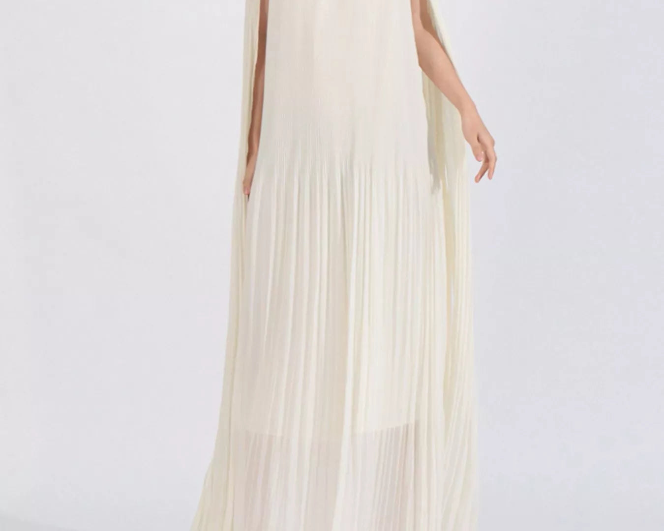 NEWYORKLISTED STYLE COLLECTION: Woman wearing a long, off-shoulder cream dress with floral details on a white background
