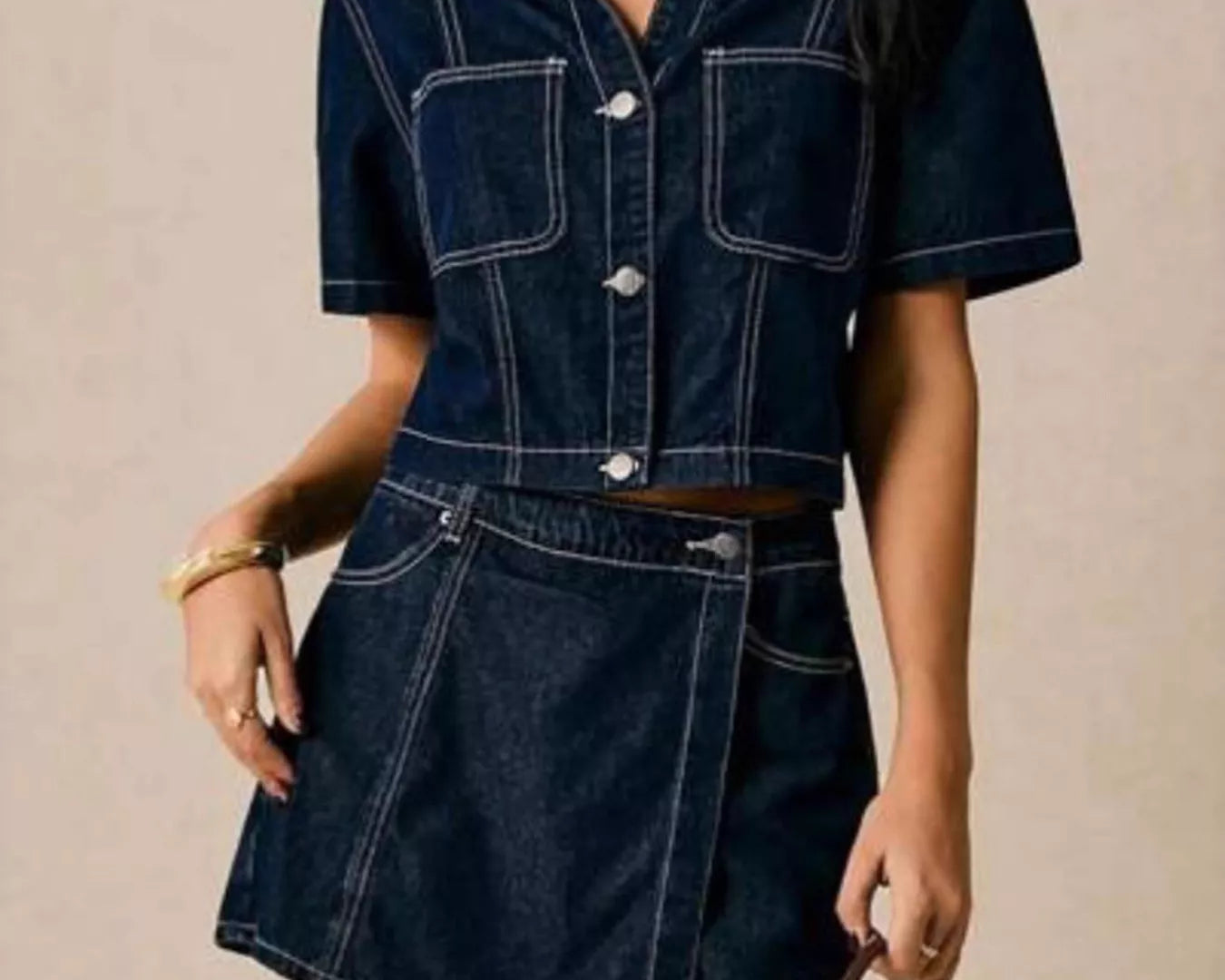 NEWYORKLISTED STYLE COLLECTION: Woman wearing a dark blue denim outfit with a beige background