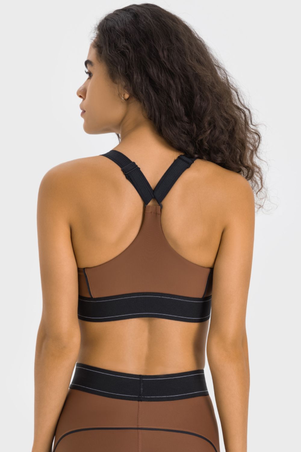 NEWYORKLISTED ACTIVEWEAR COLLECTION: Woman wearing a brown sports bra and leggings on a white background
