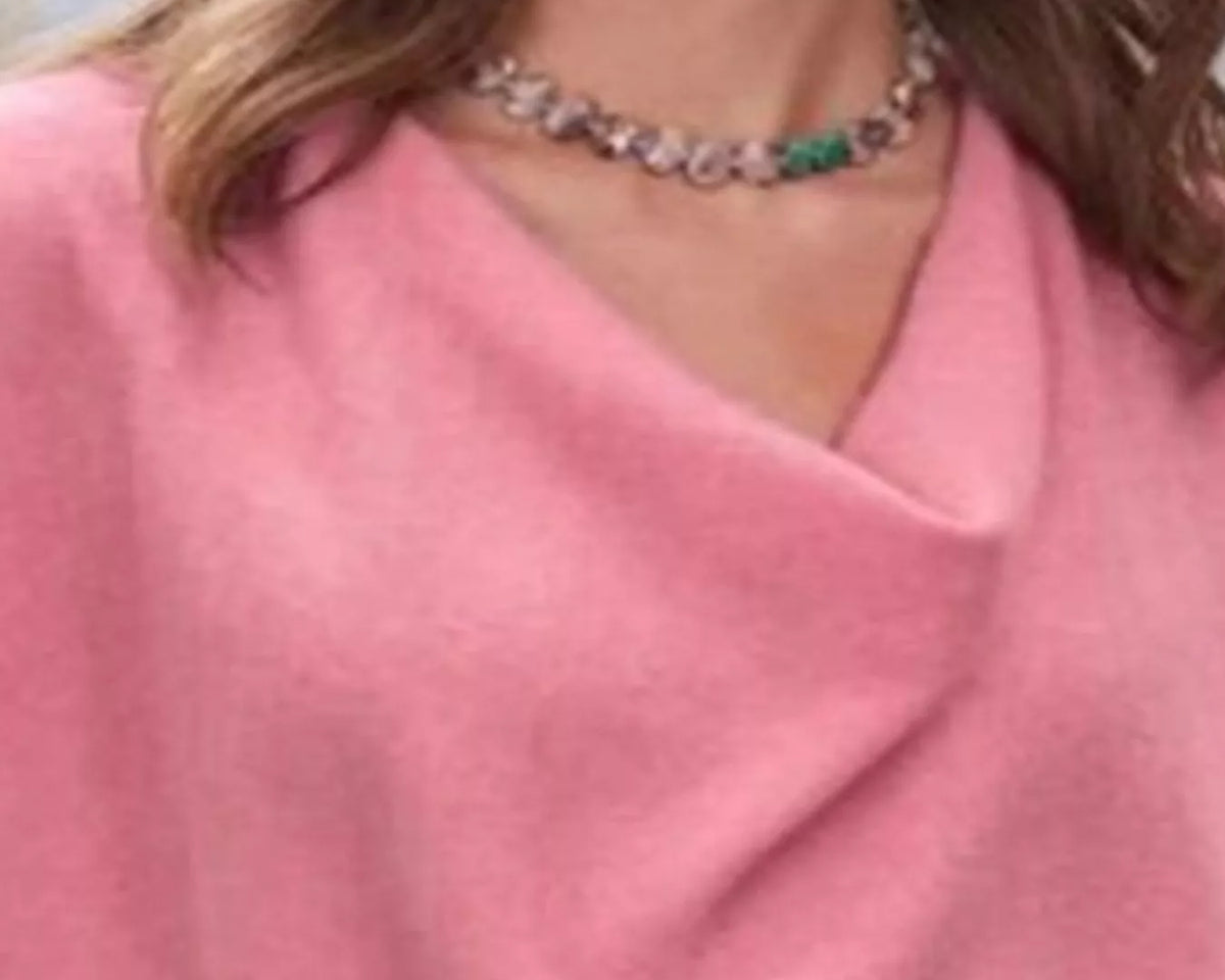 NEWYORKLISTED STYLE COLLECTION: Close-up of a person wearing a pink garment with a necklace featuring green gemstones.