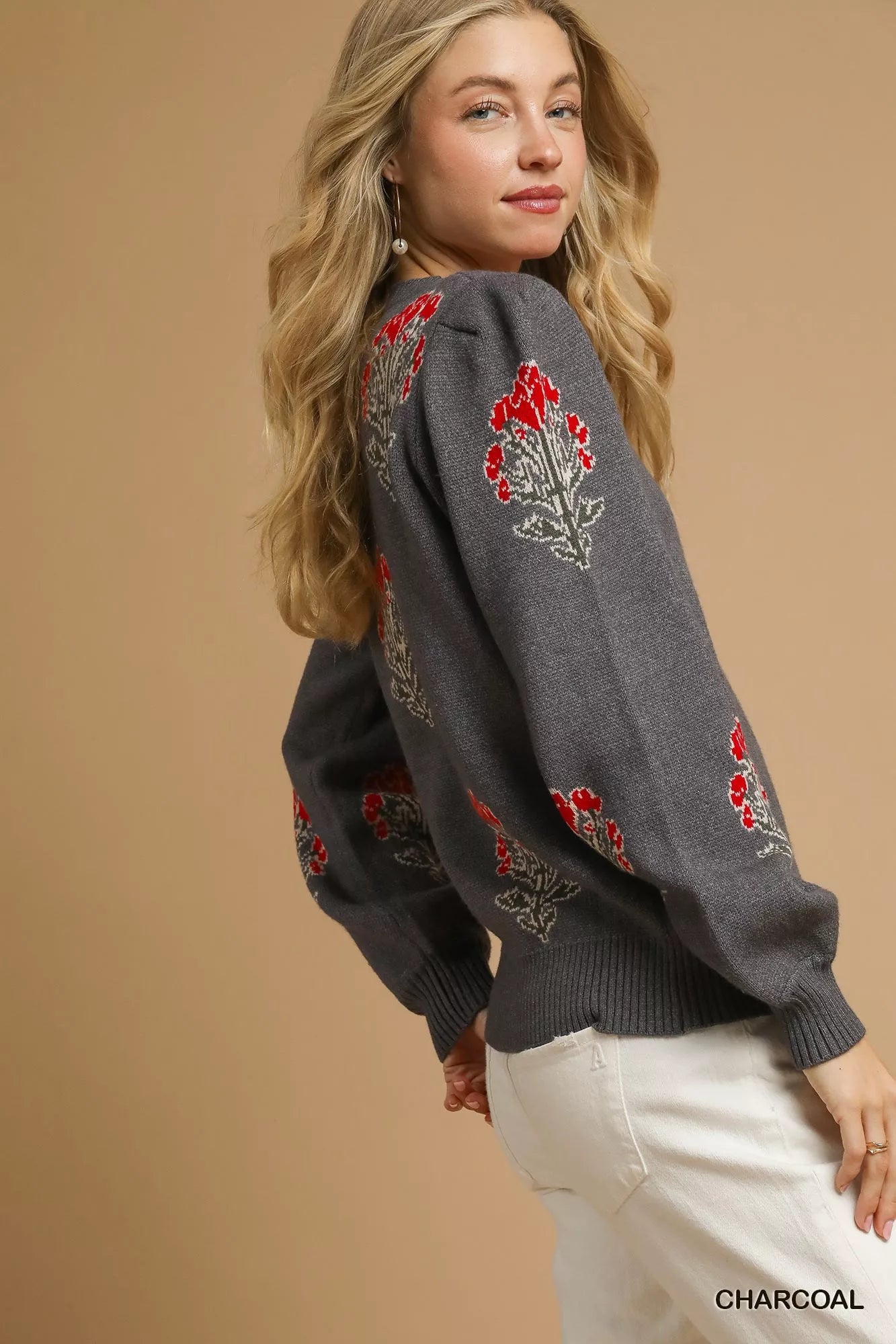 NEWYORKLISTED STYLE COLLECTION: Woman wearing a charcoal gray sweater with red floral embroidery on a beige background
