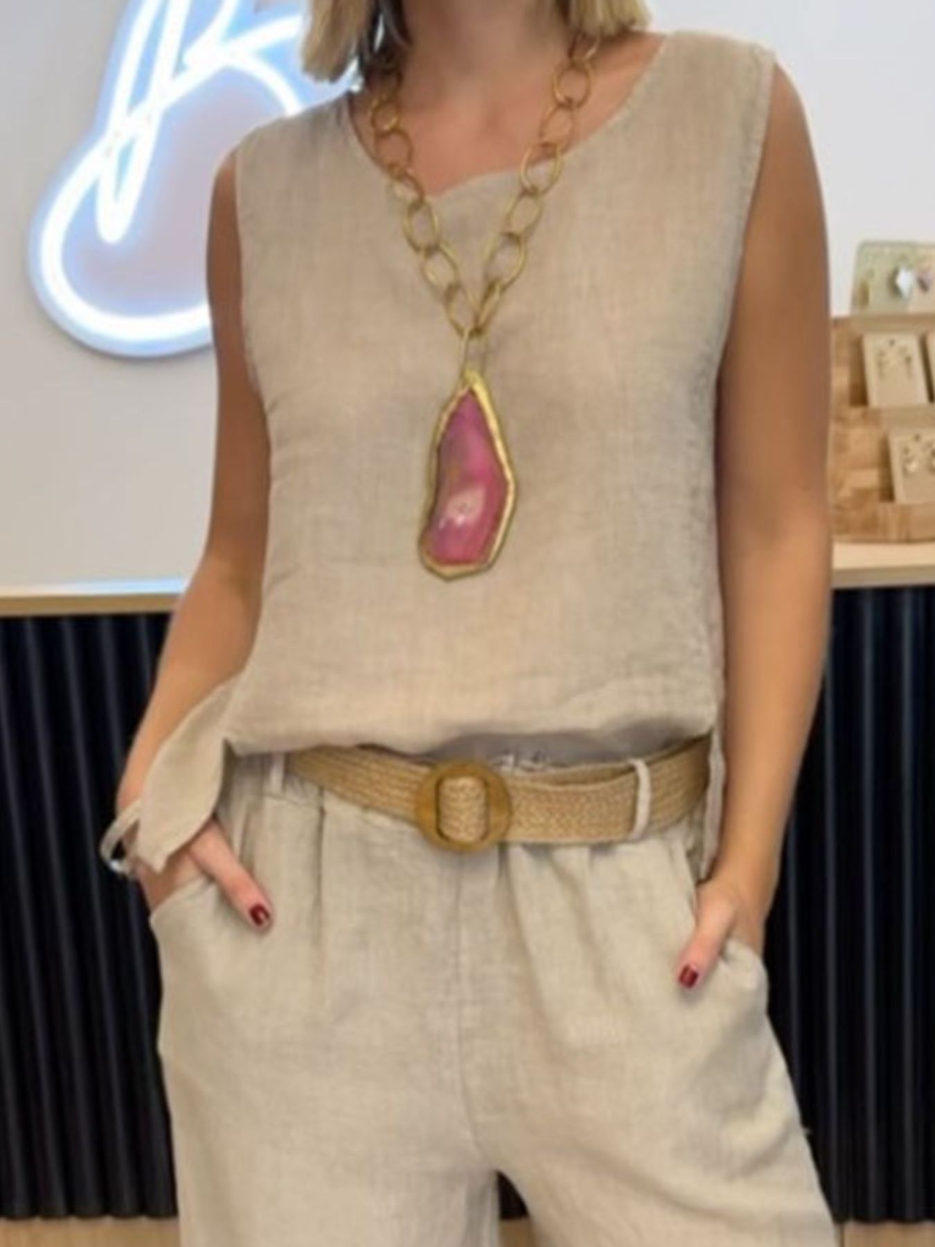 NEWYORKLISTED COMFORT COLLECTION: Person wearing a beige sleeveless top with a large necklace and beige pants in an indoor setting.