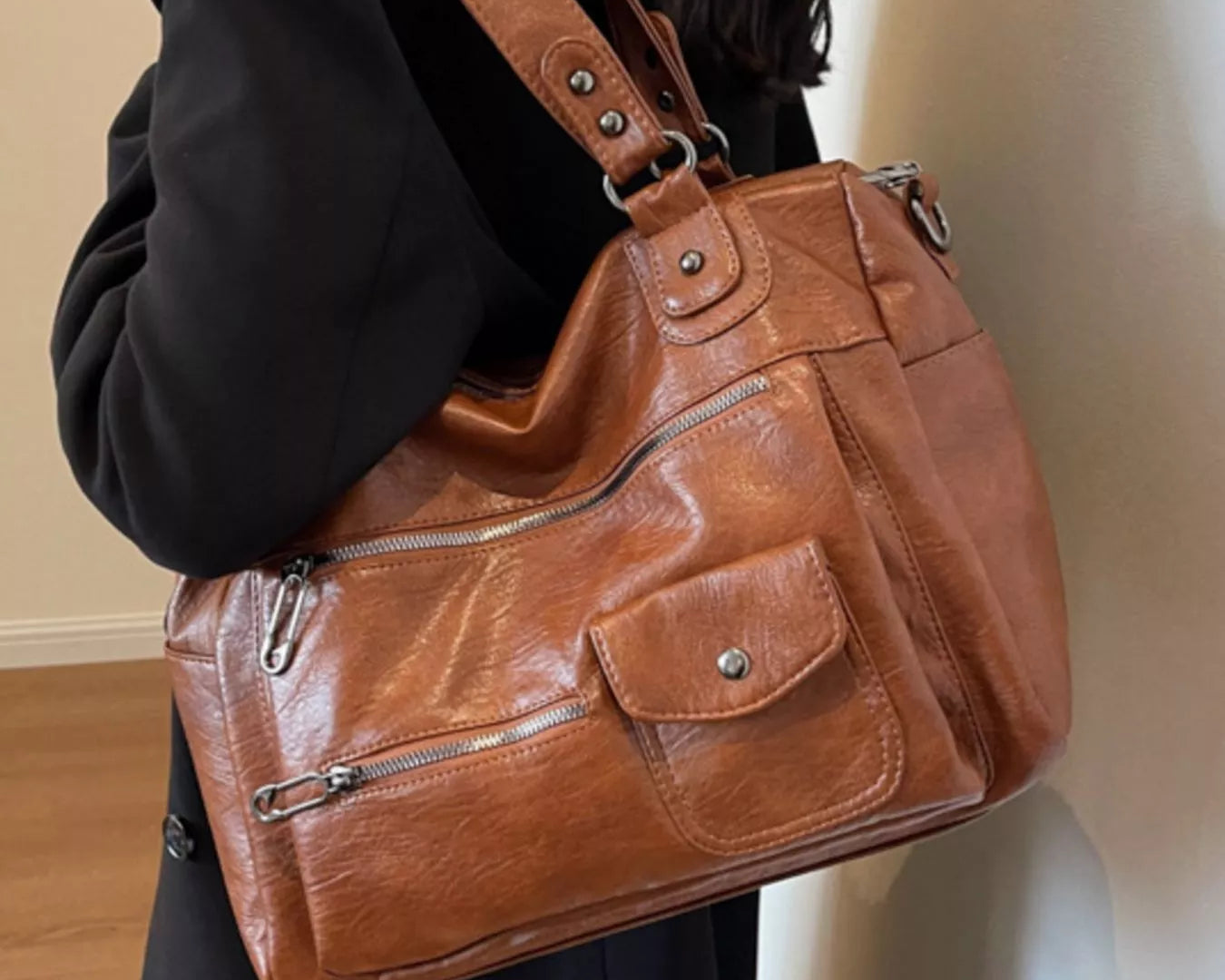 NEWYORKLISTED STYLE COLLECTION: Brown leather handbag worn by a person against a neutral background