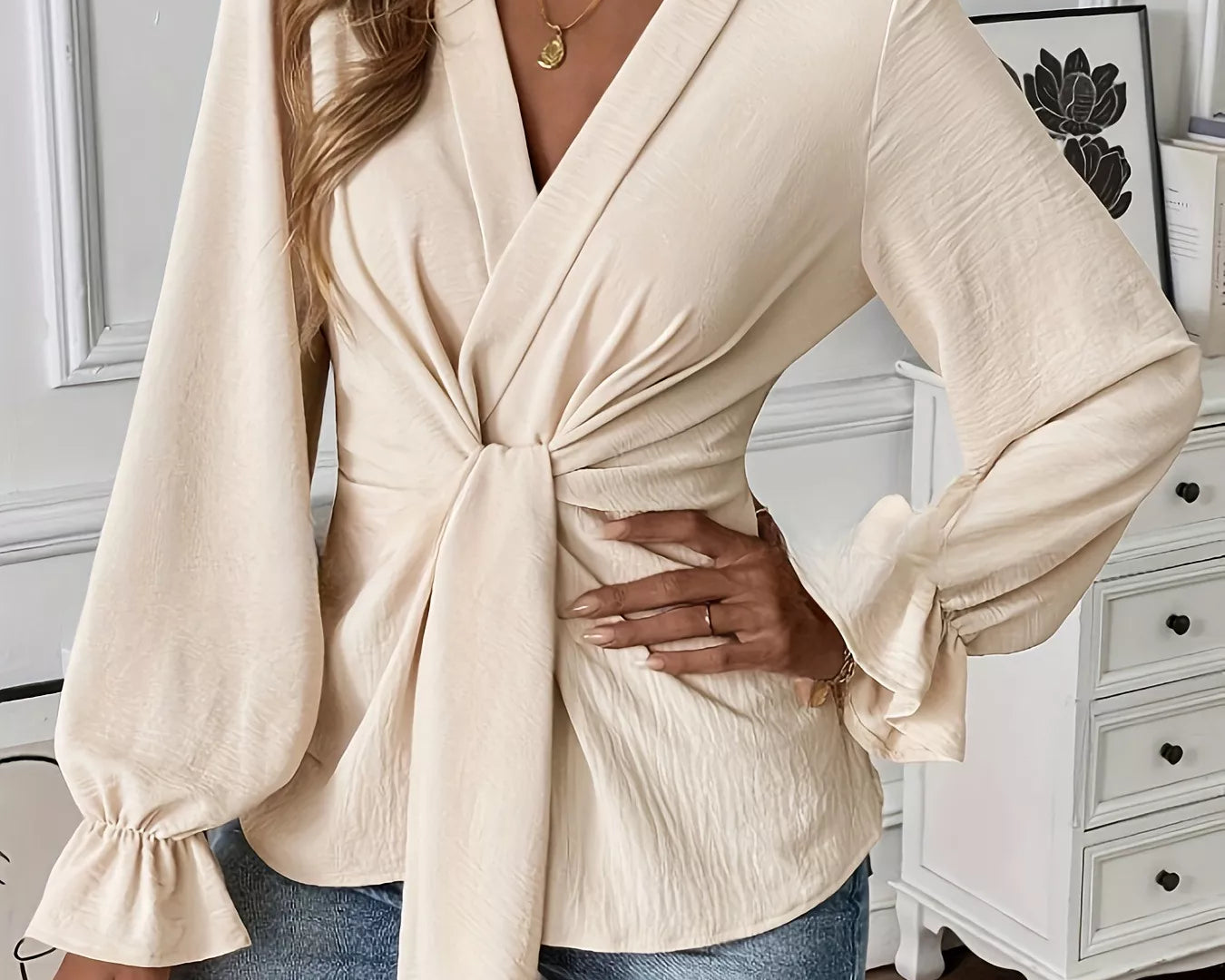 NEWYORKLISTED STYLE COLLECTION: Woman wearing a beige wrap top and blue jeans in an indoor setting.