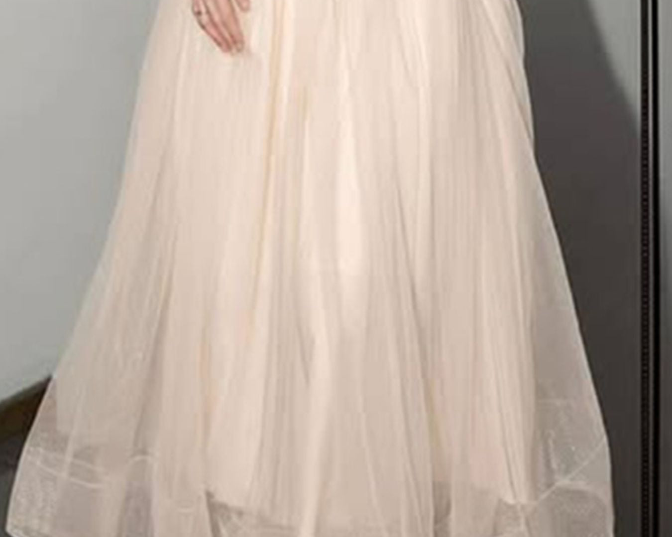 NEWYORKLISTED STYLE COLLECTION: Beige tulle skirt worn over a black top against a gray background