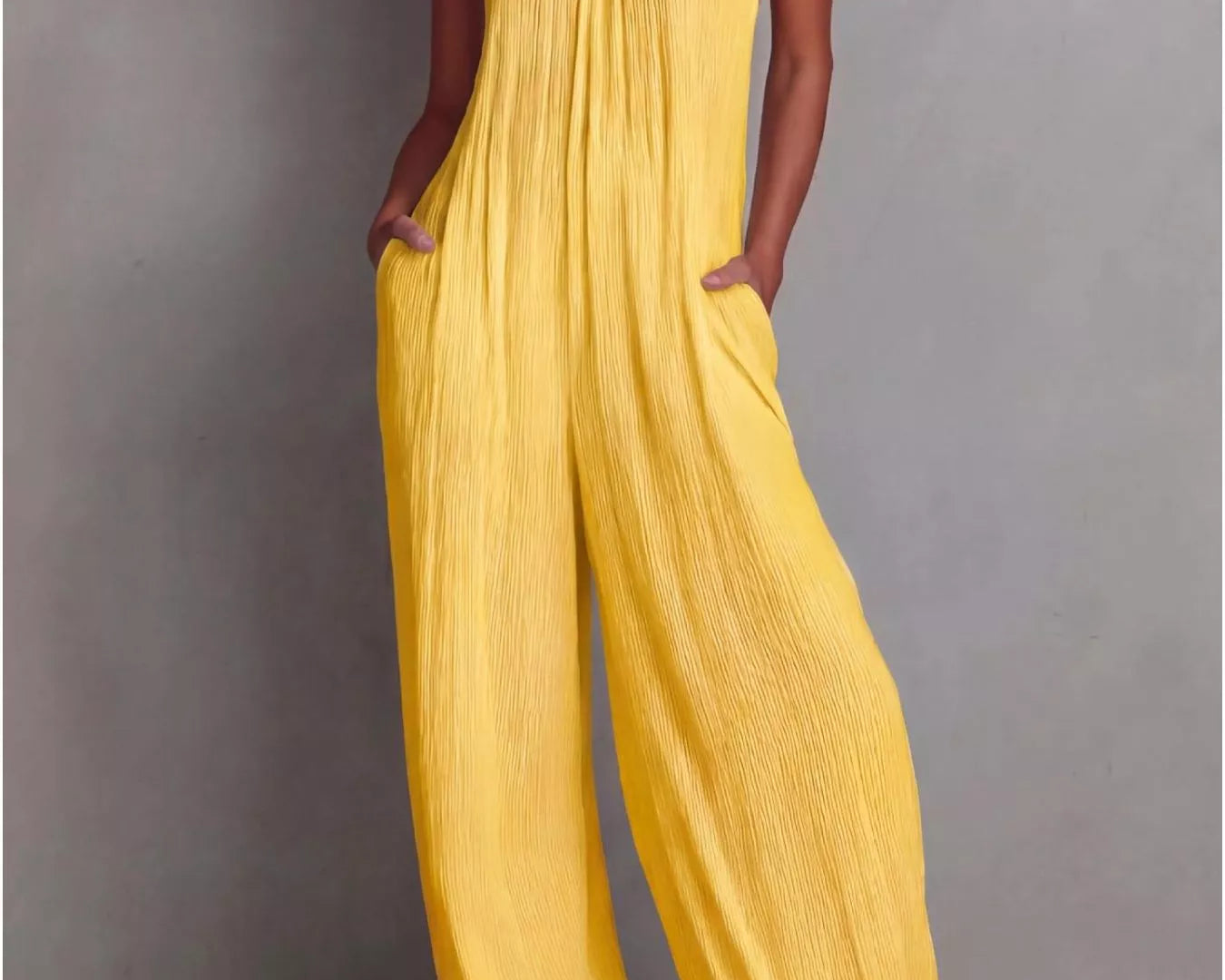 NEWYORKLISTED STYLE COLLECTION: Woman wearing a yellow jumpsuit against a gray background
