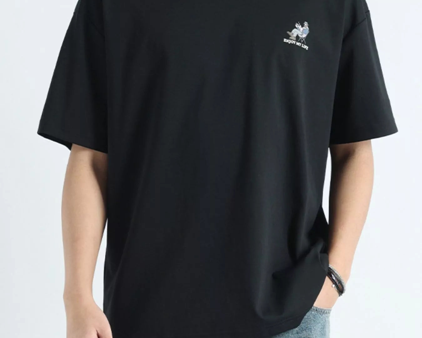 Person wearing a black t-shirt with a small logo on a white background