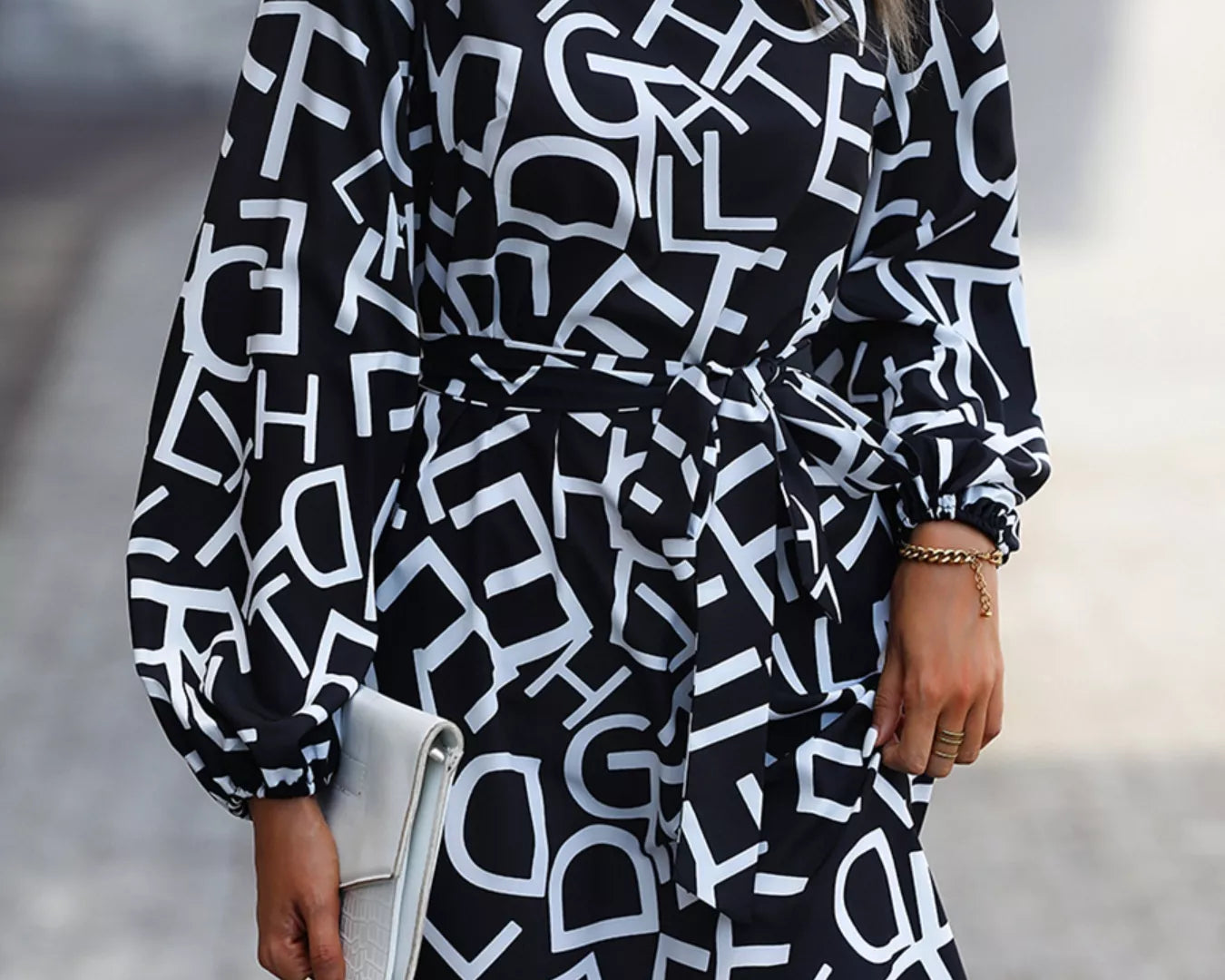 NEWYORKLISTED STYLE COLLECTION: Woman wearing a black and white patterned dress on a blurred street background