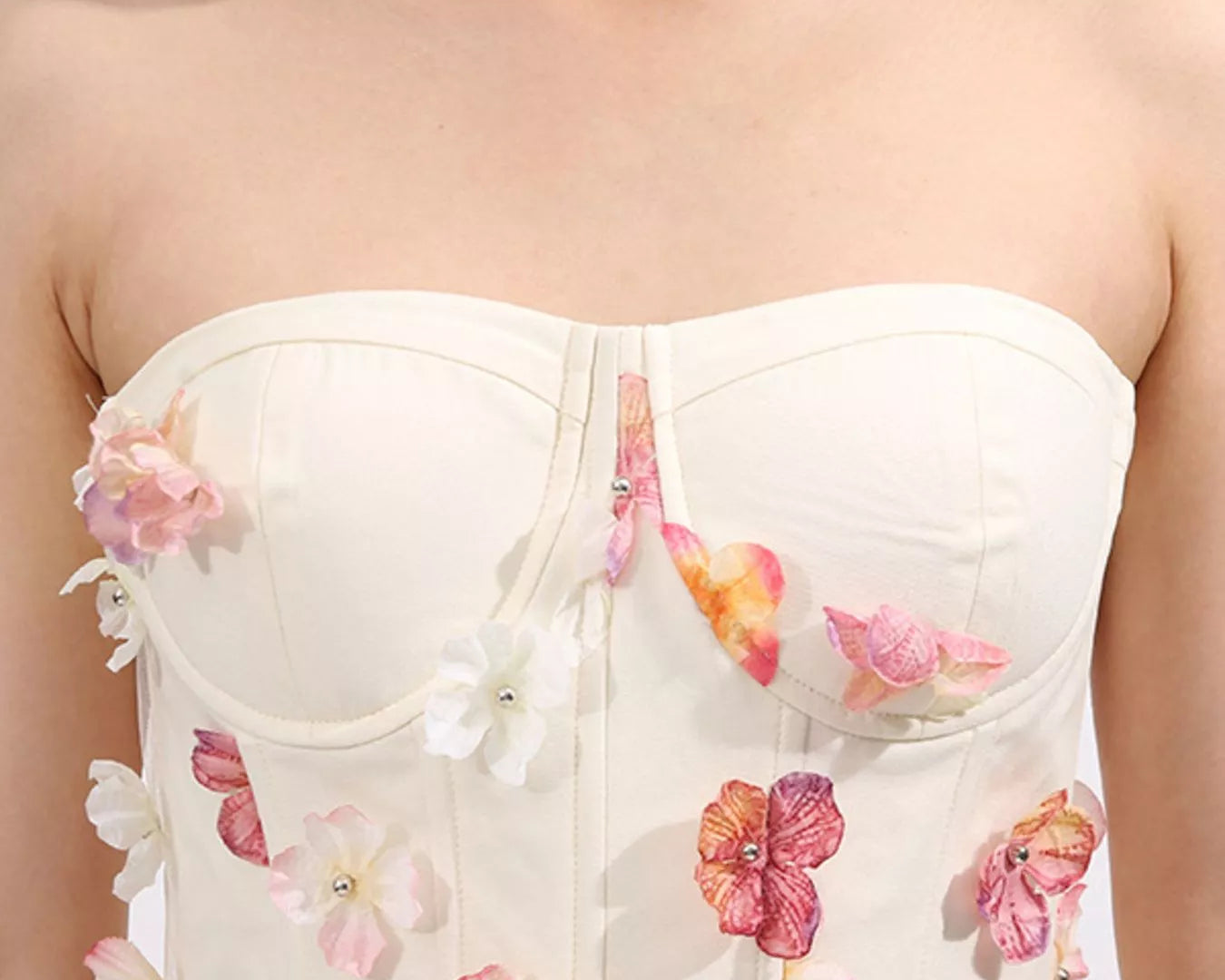 NEWYORKLISTED STYLE COLLECTION: White strapless top with floral embellishments on a plain background