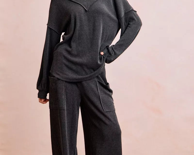 NEWYORKLISTED Comfort Collection: Woman wearing a dark gray outfit with wide-leg pants against a plain background