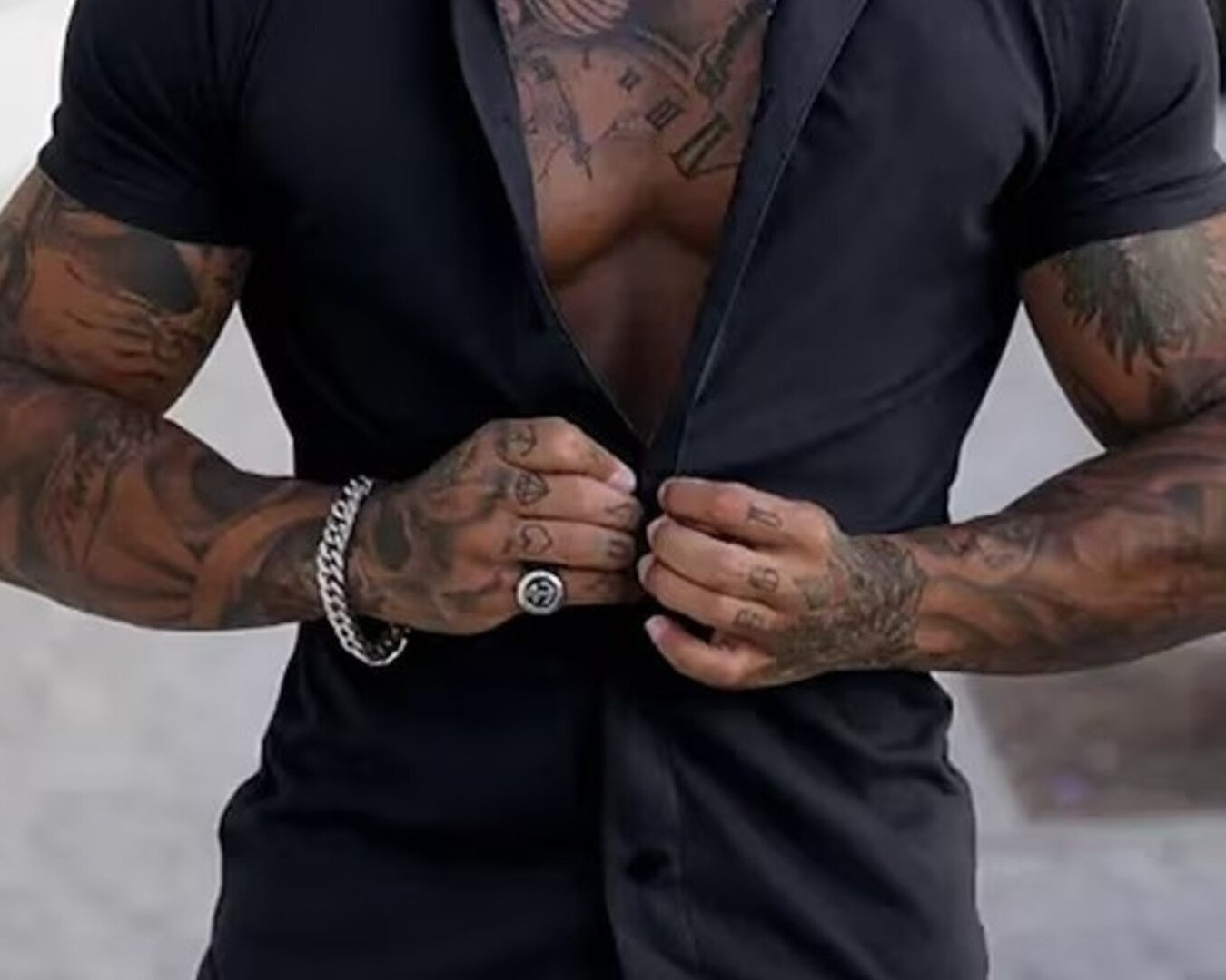 NEWYORKLISTED ATLAS MEN's COLLECTION: Man with tattoos buttoning a black shirt outdoors