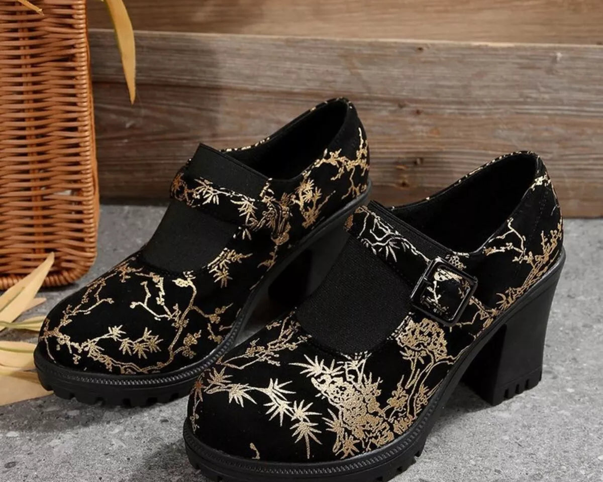 NEWYORKLISTED: Black shoes with gold floral patterns on a textured surface with a woven basket in the background.