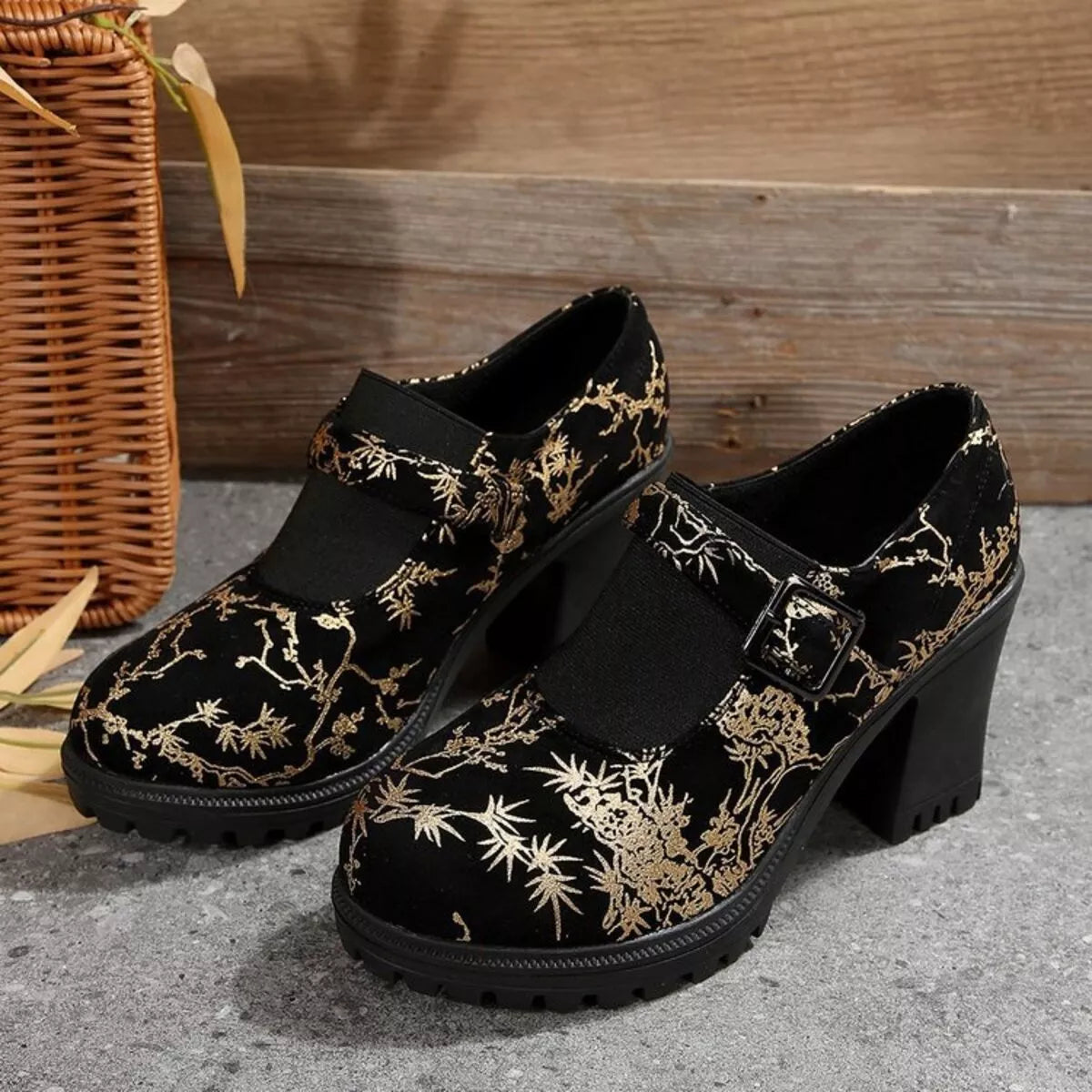 NEWYORKLISTED: Black shoes with gold floral patterns on a textured surface with a woven basket in the background.