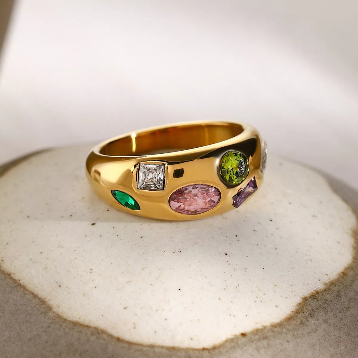 NYLD Glamour Collection by NEWYORKLISTED: Gold ring with colorful gemstones on a textured surface