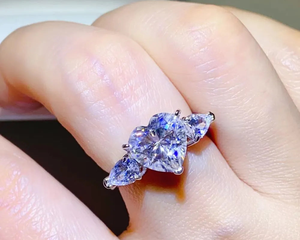 NYLD Glamour Collection By NEWYORKLISTED: Close-up of a hand wearing a silver ring with a large purple gemstone.