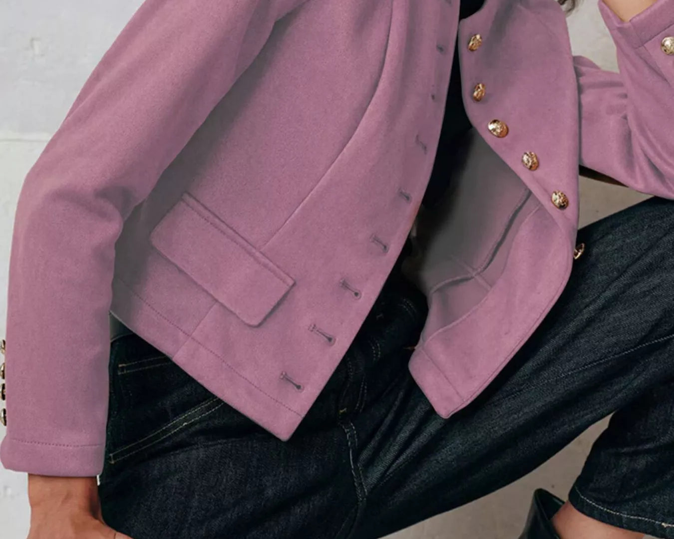 NEWYORKLISTED Style Collection Person wearing a pink jacket with gold buttons and dark jeans against a light background