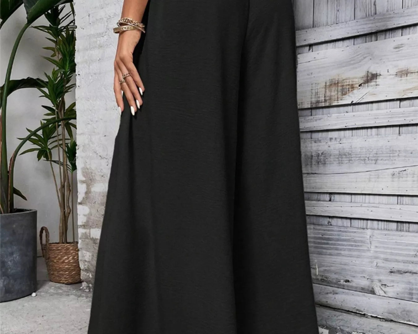 NEWYORKLISTED STYLE COLLECTION: Person wearing black wide-leg pants standing against a wooden wall.