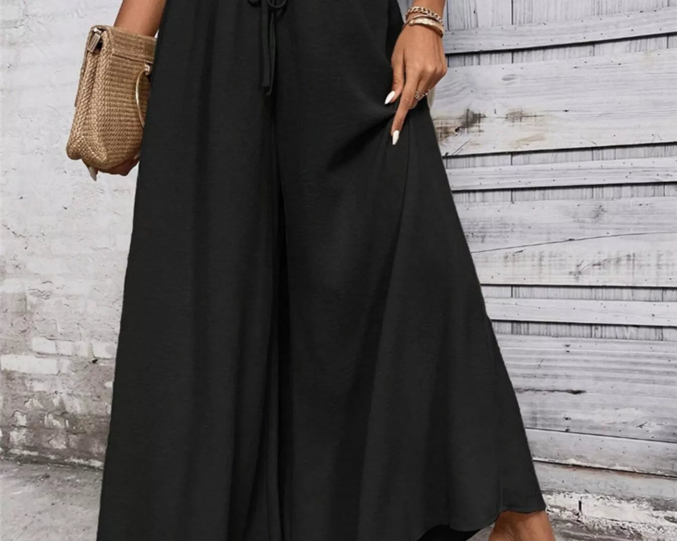NEWYORKLISTED STYLE COLLECTION: Person wearing black wide-leg pants with a white top against a wooden wall.