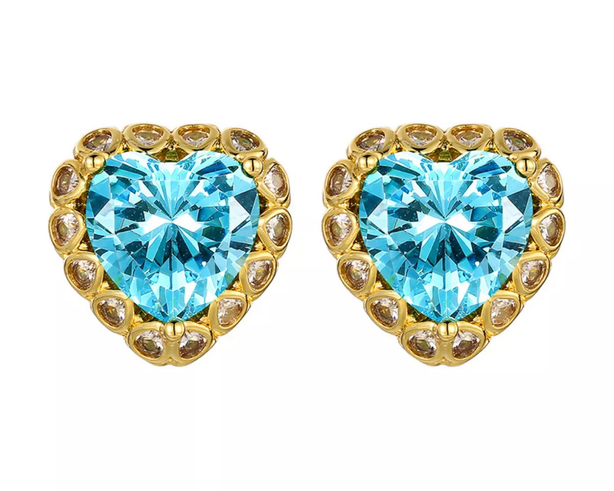 NYLD Glamour Collection by NEWYORKLISTED: Heart-shaped blue gemstone earrings with gold accents on a white background