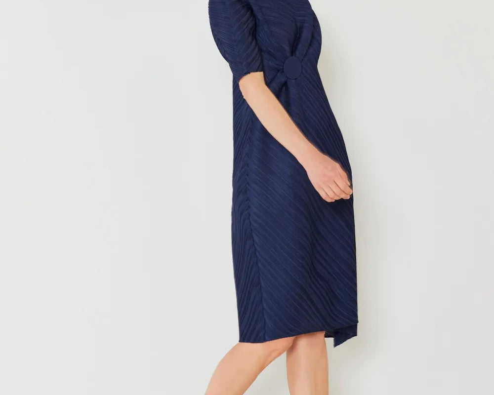 Woman wearing a navy blue dress against a white background: NEWYORKLISTED STYLE COLLECTION