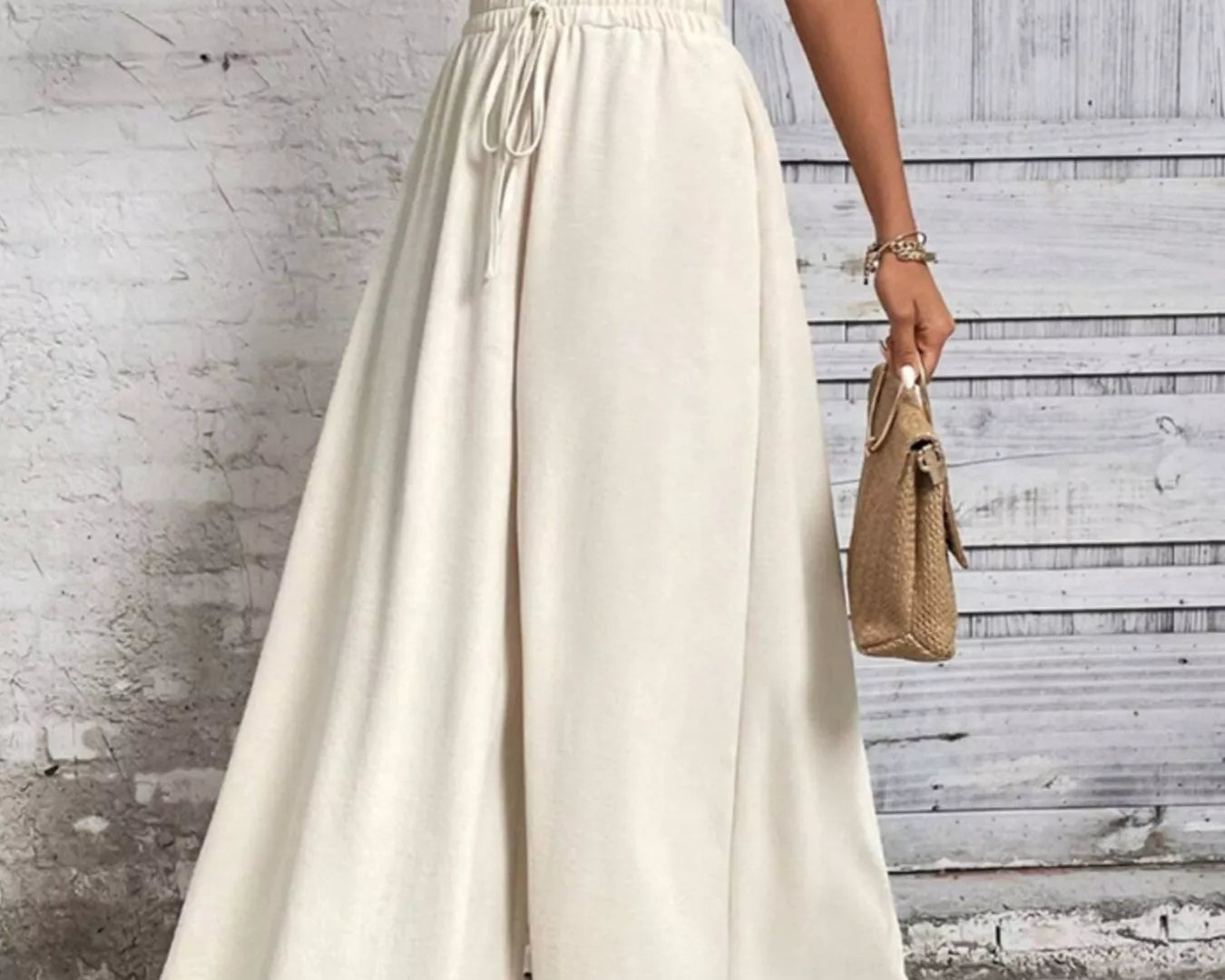 NEWYORKLISTED: Person wearing a white top and long beige skirt against a light gray background