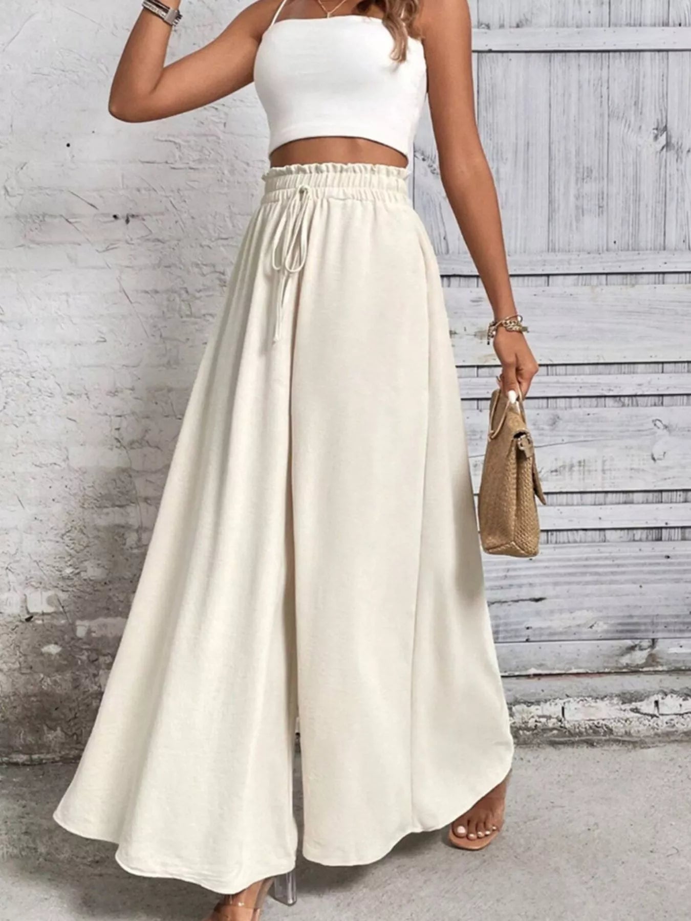 NEWYORKLISTED: Person wearing a white top and long beige skirt against a light gray background