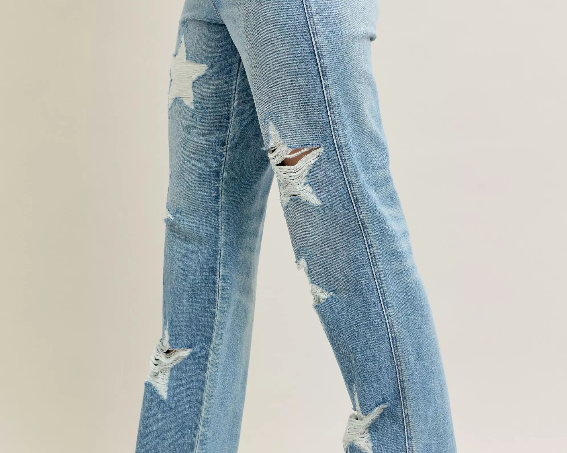 NEWYORKLISTED STYLE COLLECTION: Light blue distressed jeans worn by a person on a plain background