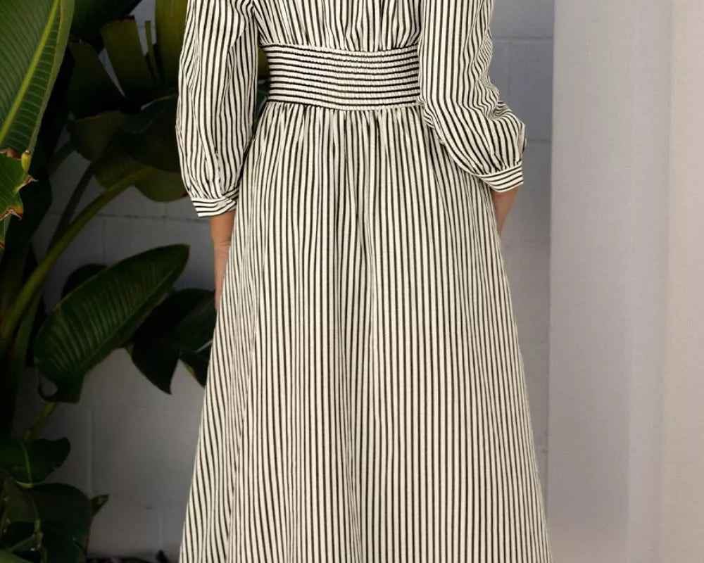 NEWYORKLISTED STYLE COLLECTION: Woman wearing a striped dress standing in a room with plants.