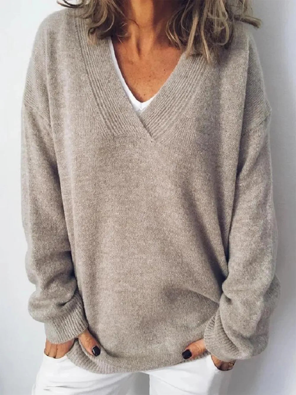 NEWYORKLISTED STYLE COLLECTION: Person wearing a beige sweater over a white shirt against a plain background