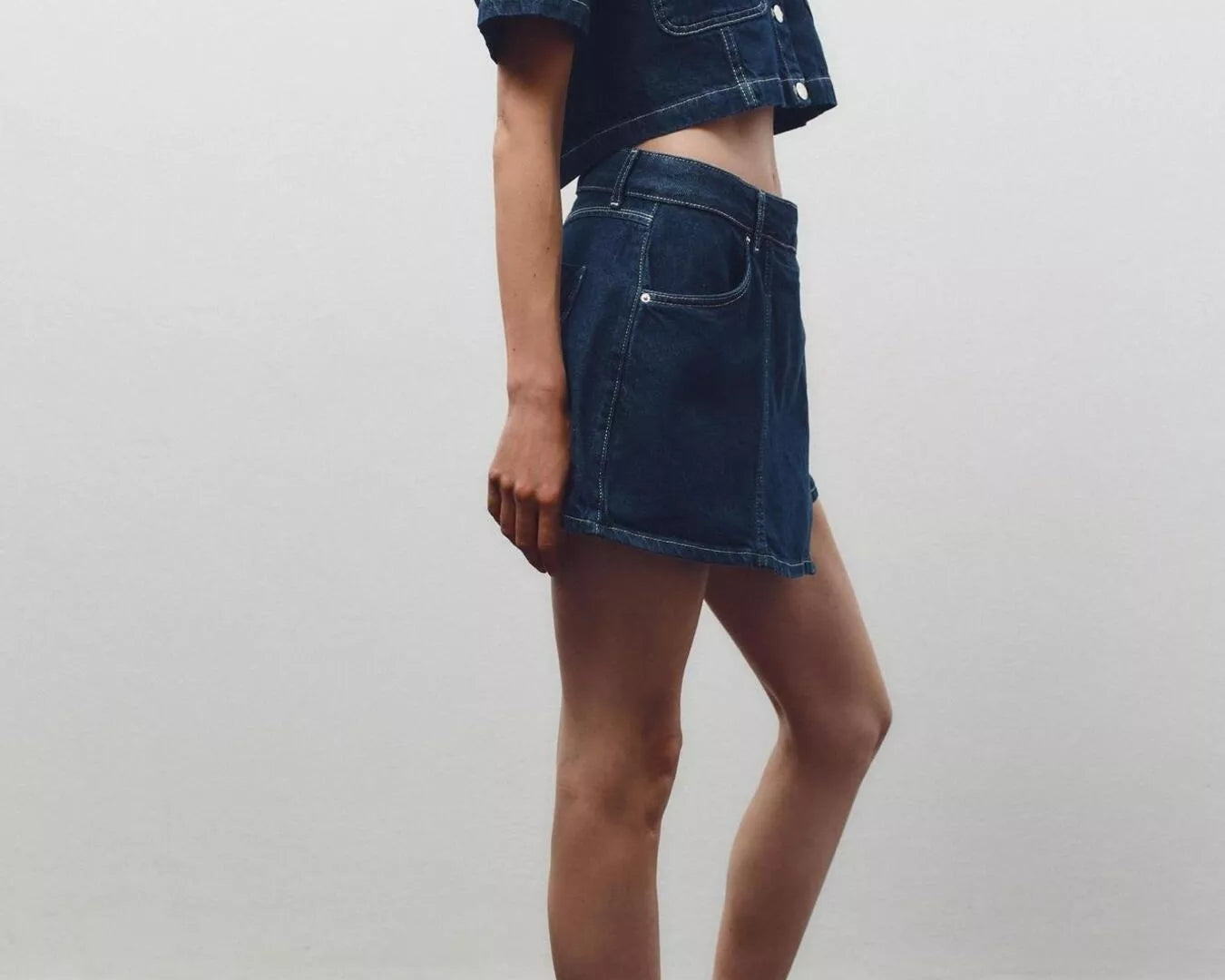 NEWYORKLISTED STYLE COLLECTION: Person wearing a denim outfit with a skirt and jacket against a plain background