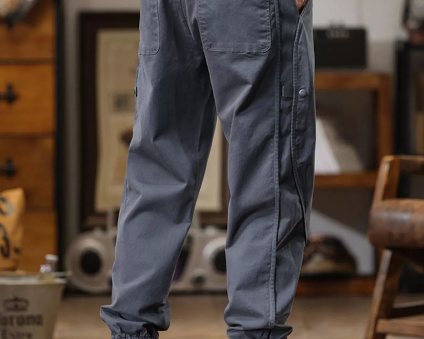 NEWYORKLISTED ATLAS MEN'S COLLECTION: Person wearing gray cargo pants and yellow boots in a room with wooden furniture.