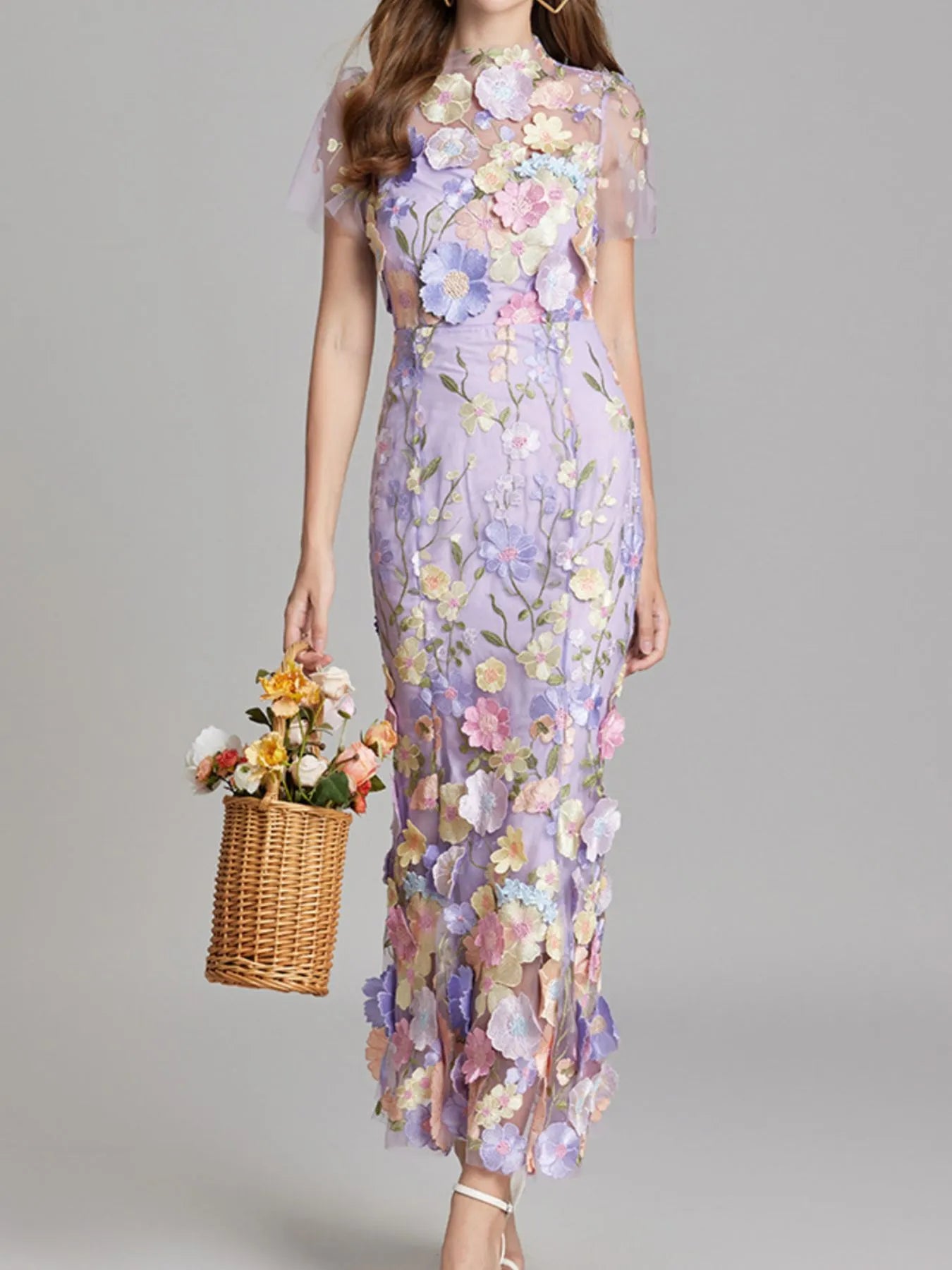 NEWYORKLISTED STYLE COLLECTION: Woman wearing a floral dress holding a basket of flowers against a gray background