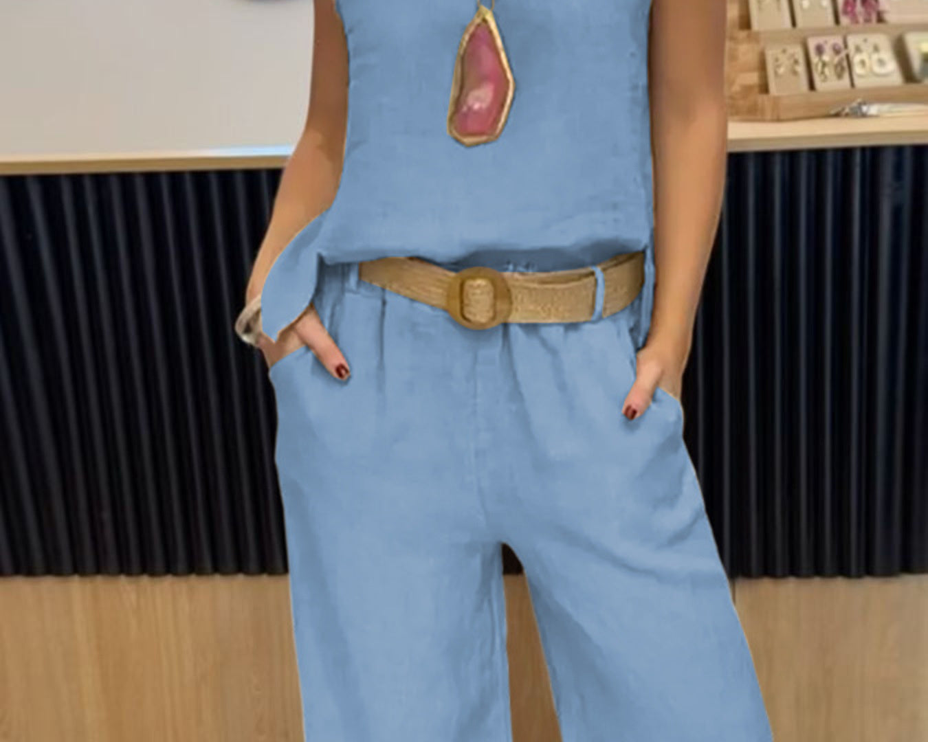 NEWYORKLISTED COMFORT COLLECTION: Person wearing a blue sleeveless top and pants with a belt, standing indoors.
