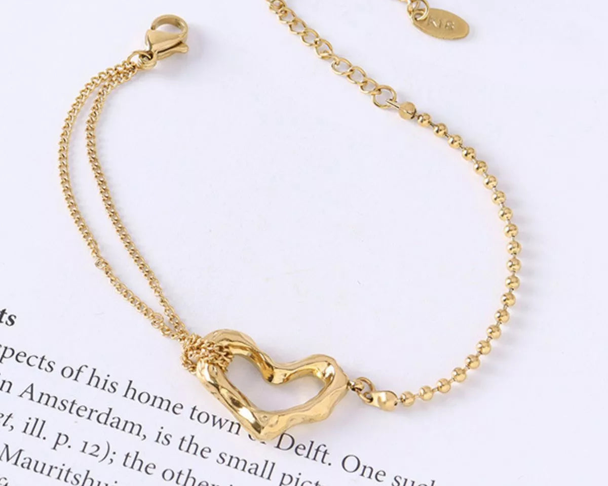 NYLD Glamour Collection by NEWYORKLISTED: Gold bracelet with a heart-shaped clasp on a white background