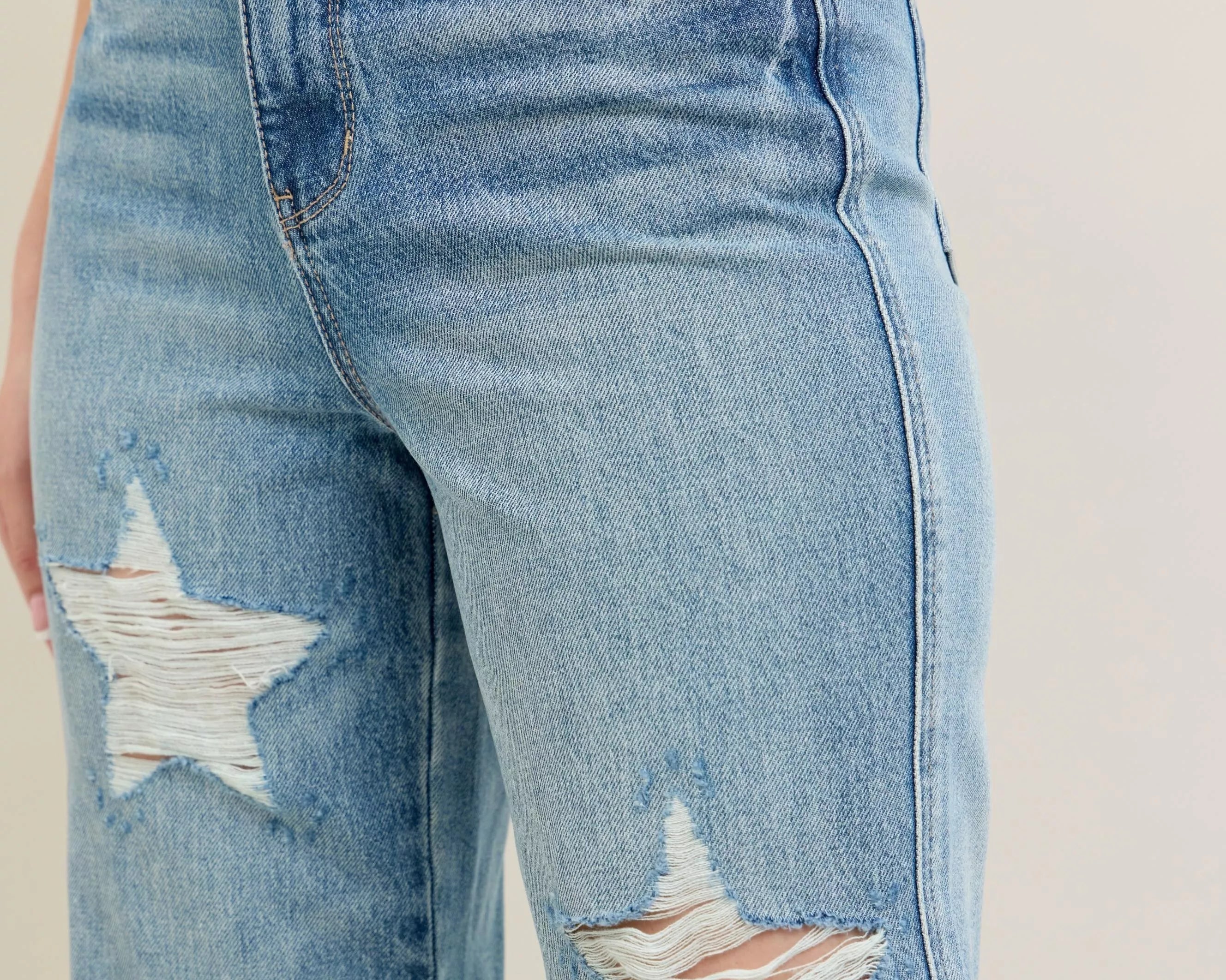 NEWYORKLISTED STYLE COLLECTION: Distressed blue jeans with star designs on a neutral background