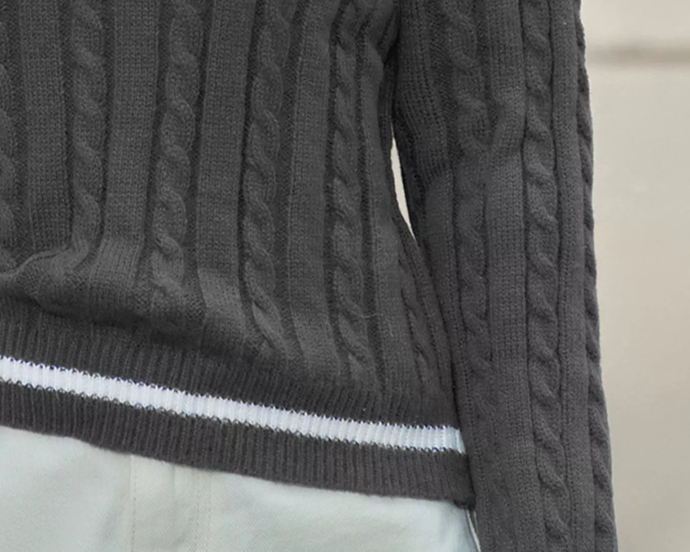 NEWYORKLISTED STYLE COLLECTION: Dark gray cable knit sweater with white trim on a neutral background