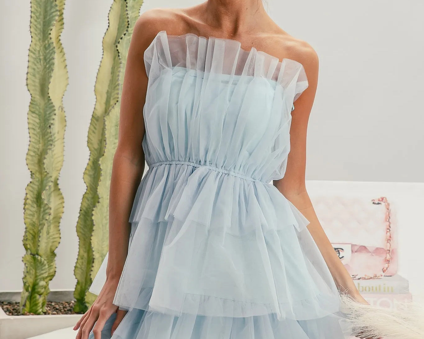 NEWYORKLISTED STYLE COLLECTION: Sleeveless Layered Organza Dress Woman wearing a light blue strapless dress with sunglasses indoors.